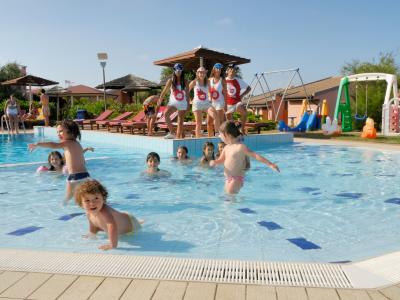 Bambini che giocano in piscina con animatori in un resort.