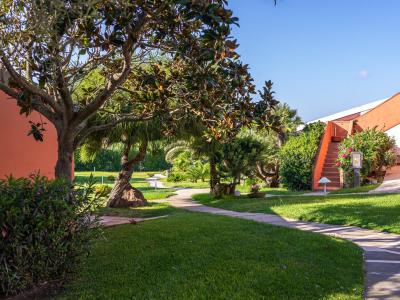 Giardino con sentiero, alberi e edificio arancione.