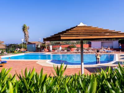Piscina all'aperto con ombrelloni, persone che si rilassano.
