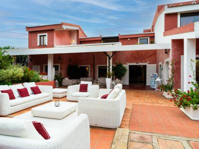 Elegante terrazza con divani bianchi, cuscini rossi e piante fiorite.