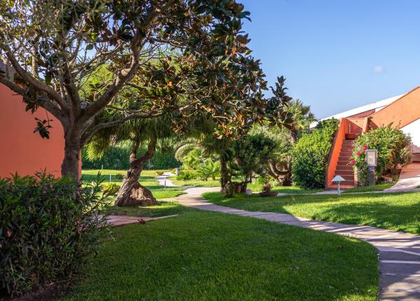 Giardino con sentiero, alberi e edificio arancione.