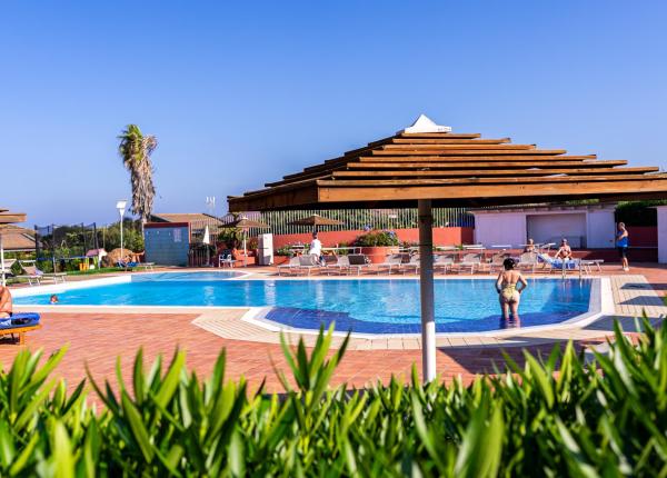 Piscina all'aperto con ombrelloni, persone che si rilassano.