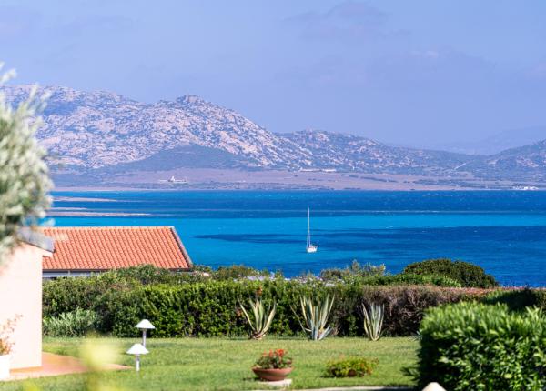 Vista mozzafiato su mare turchese, barca a vela e montagne.